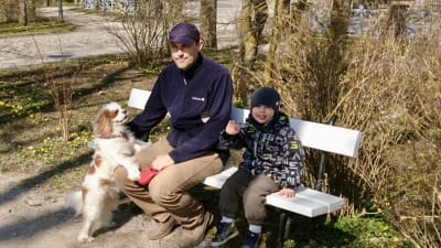 Pappa Liigsoo med sin son och hunden Lotte sitter på en parkbänk i Kuressaare på Ösel i Estland.