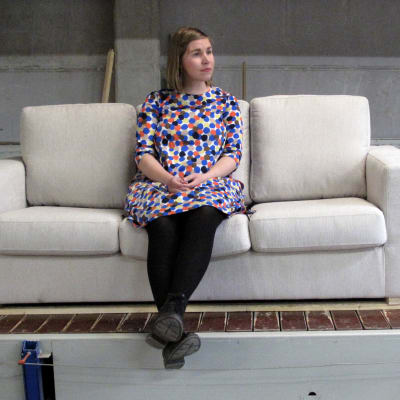 Nainen istuu sohvalla huonekalutehtaalla.