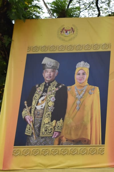 Porträtt av kungen och drottningen kan man se vid vägkanter, på arbetsplatser och i otaliga hem. Klädseln återspeglar deras roll som beskyddare av den malajiska kulturen och av islam.