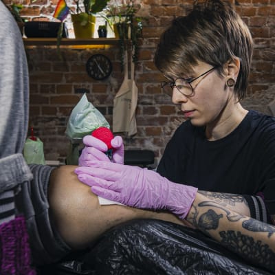 Sopu -tatuointistudion tatuoija Iina Räsänen tatuoi asiakkaan polvea.