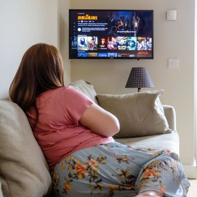 En kvinna sitter på soffan och kollar på Netflix.