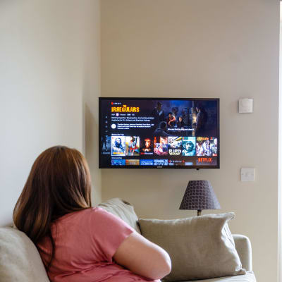En kvinna sitter på soffan och kollar på Netflix.