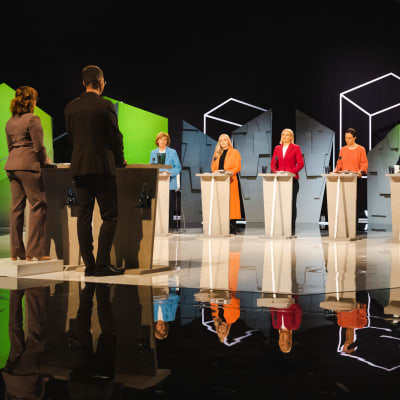 Åtta patiordförande uppställda i tv-studio för en valdebatt. 