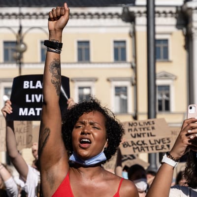 En kvinna i röd topp håller upp knytnäven under Black Lives Matter-demonstrationen.