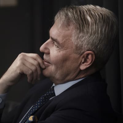 Pekka Haavisto sitter på en stol och tittar åt sidan.