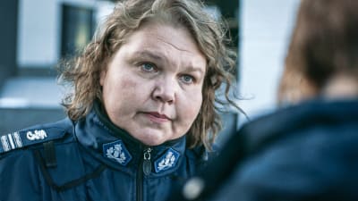 Näyttelijä Kaarina Hazard poliisin univormussa katsoen toista ihmistä silmiin.