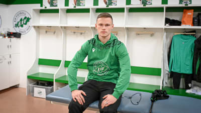 En man sitter på en bänk klädd i fotbollslaget EIF:s gröna tröja. Han heter Tobias Fagerström.