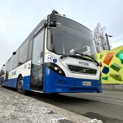 Sininen Nysse-bussi kuvattuna pysäkillä alhaalta käsin. 