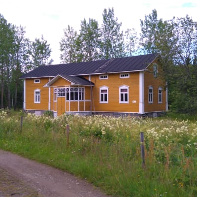 Pahnilan keltainen museorakennus, etualalla kesäinen niitty