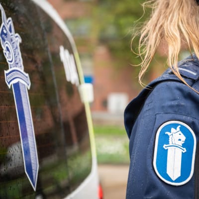 En del av en polisbild syns i bild samt en polis arm i uniform.