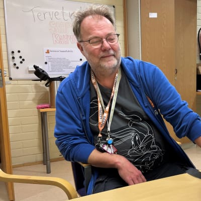 Miehellä on edessään  pöydällä reppu.