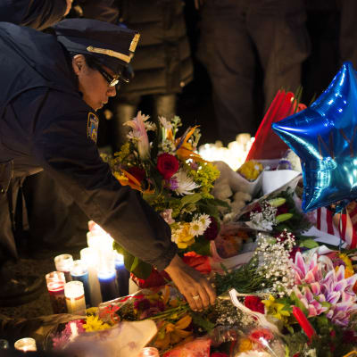 En polis lämnar blommor på minnesplatsen för de två poliserna som dödades i New York.