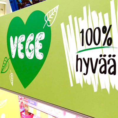 Vegaanisia tuotteita sisältävän elintarvikehyllyn tunnuslogo: vihreä sydän ja teksti 100% hyvää.