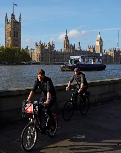 Två cyklister vid Themsens strand. I bakgrunden syns Westminster och Big Ben.