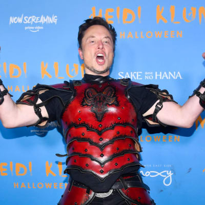 Naamiaisasuun pukeutunut Elon Musk näyttää hauiksiaan.