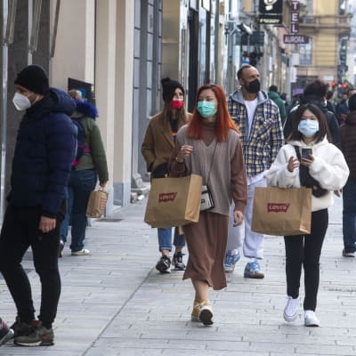 Personer går på en shoppinggata i Italien, iklädda munskydd.