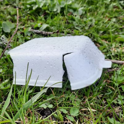 En lunchbox i plast som ligger slängd på en gräsmatta.