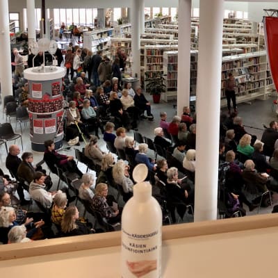 Publik på Mariehamns litteraturdagar, flaska med handsprit i förgrunden.