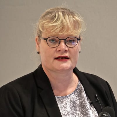 Katrin Sjögren står och pratar vid en dator