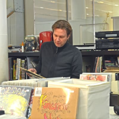 Mikael Winogradow visar vinylskivor som han håller i åt en kund.