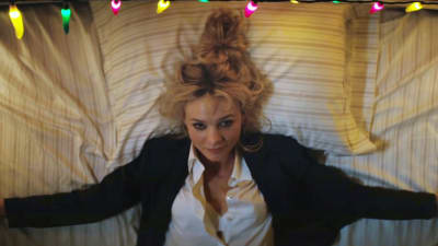 Cassandra (Carey Mulligan) ligger på rygg i en säng med armarna utsträckta och ser klurig ut.