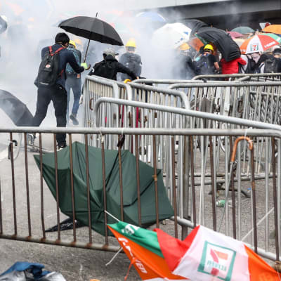 Demonstranter flyr polisens tårgas i Hongkong. 