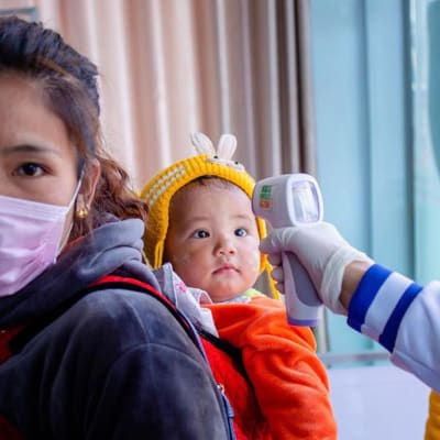 Kiinaan matkustavat tutkitaan nyt tarkkaan. Tässä terveysviranomaiset syynäävät lapsen ruumiin lämpötilaa Myanmarin ja Kiinan rajalla.
