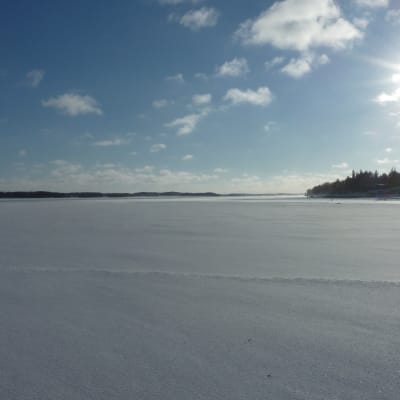 Solen skiner över isen på Skärgårdshavet en vinterdag.