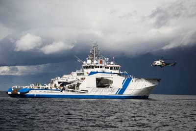 Räddningshelikopter landar på en patrullbåt ute till havs. 