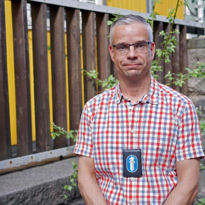Äldre poliskonstapel Niklas Kråknäs i somrig skjorta, med polisbricka runt halsen.