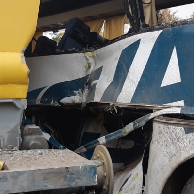 Koululaisia kuljettanut linja-auto johon on törmännyt ratakuorma-auto. lähikuva pellistä.