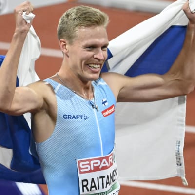 Topi Raitanen tuulettaa Suomen lipun kanssa.