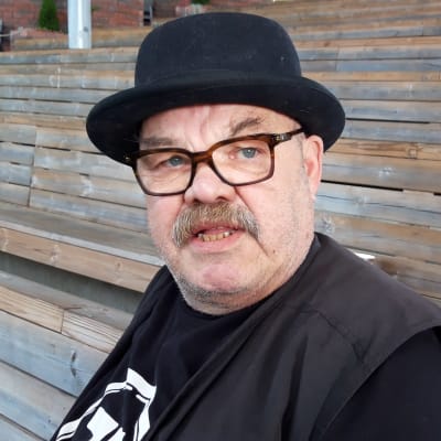 Jaakko Teppo istuu tyhjän kesäteatterin katsomossa knallihattu päässään.