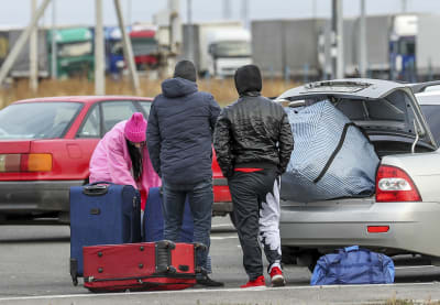 Tre personer står på en parkeringsplats med ryggarna mot kameran. 