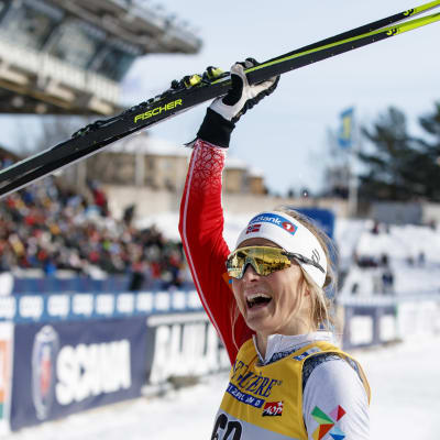 Therese Johaug vinkar med sina skidor.