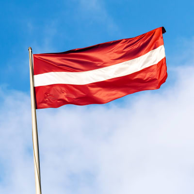 Lettlands flagga framför blå himmel.