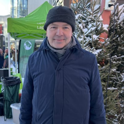 Ulkoministeri Pekka Haavisto seisoo Rovaniemen Lordin-aukiolla. On talvi ja Haavistolla pipo päässä. Taustalla näkyy vihreiden vaaliteltta ja kuusia.