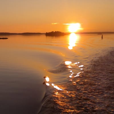 Solnedgång i Åbolands skärgård med solen glittrande på vågsvall.