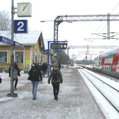 Människor går på perrongen på järnvägsstationen i Karis.