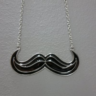 En Movember-mustasch som hängsmycke.