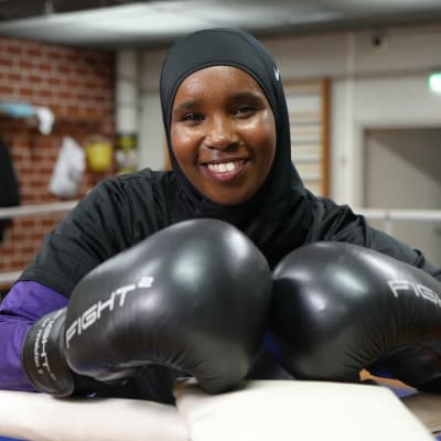 Nainen, jolla on nyrkkeilyhanskat kädessä ja hijab päässä.
