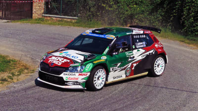 En rallybil susar fram i en brant kurva.