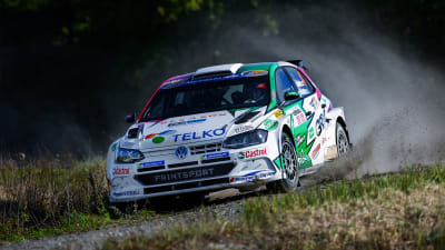 En rallybil susar fram på en grusväg.