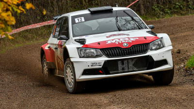 En rallybil susar framåt på en grusväg.
