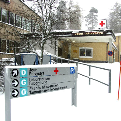 En snöig informationsskylt utanför ett sjukhus i vinterlandskap.