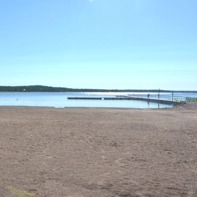 På bilden en nästan tom sandstrand och blå himmel