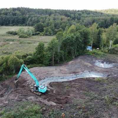 En grävmaskin som bygger en våtmark i Sjundeå.