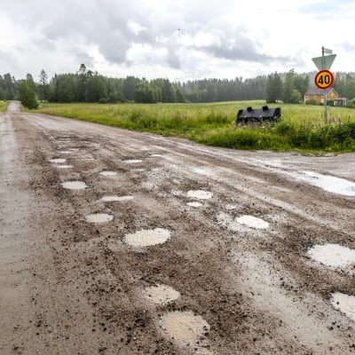 Kuoppainen soratie, vettä sataa.