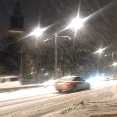 Bilar kör i snöyra och förbi Åbo domkyrka och höga snövallar.