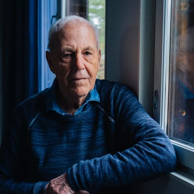Caj Bremer står i mörkblå tröja vid ett fönster.
